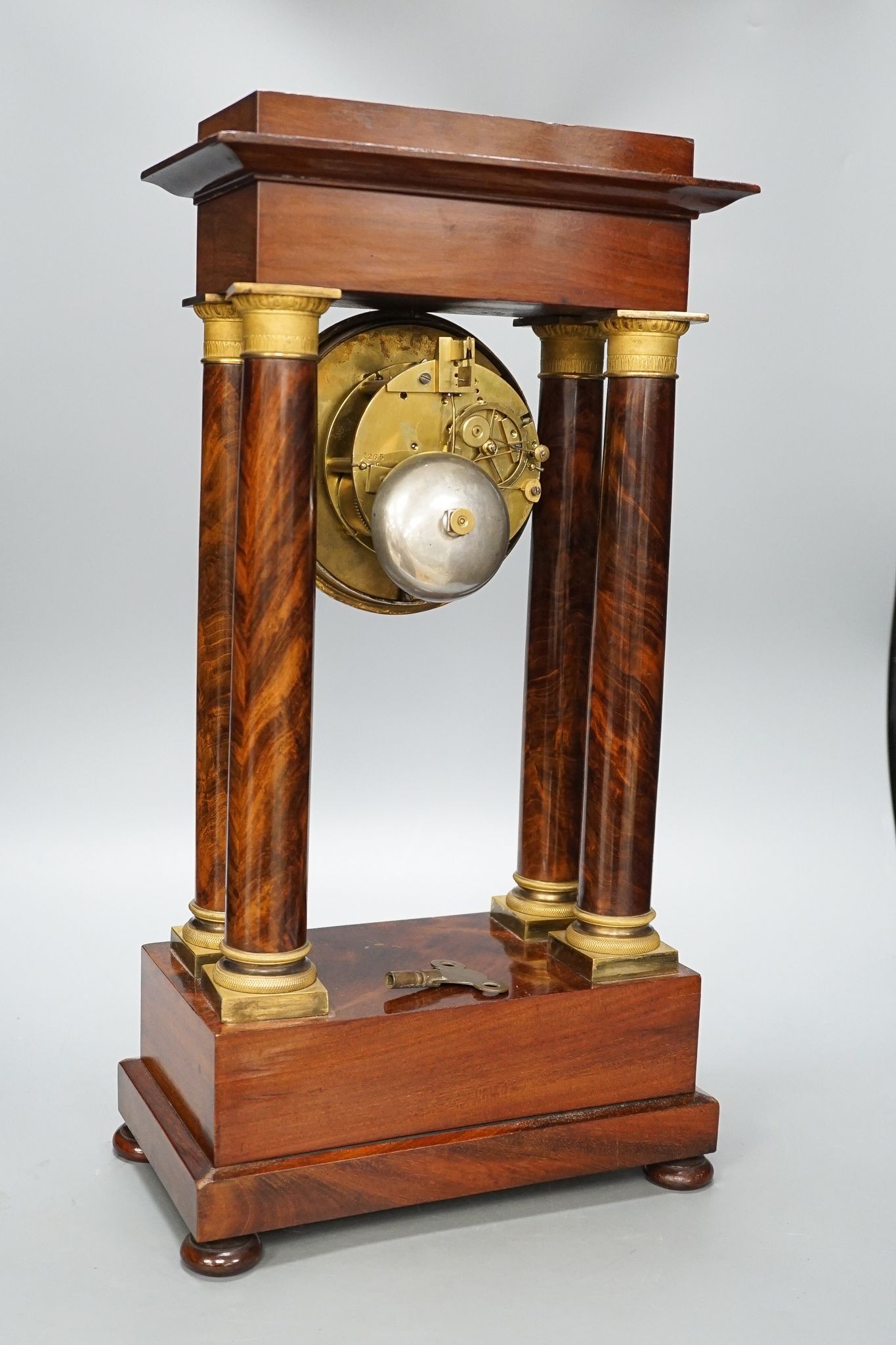 An early 19th century mahogany portico clock with three keys and spare bell, 50cm